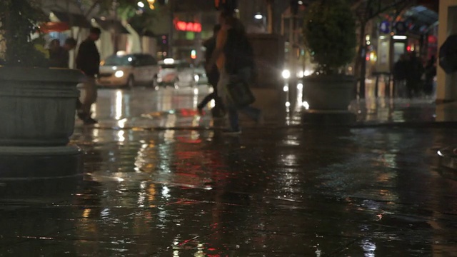 人们在雨中行走和奔跑在夜晚的街道上视频素材