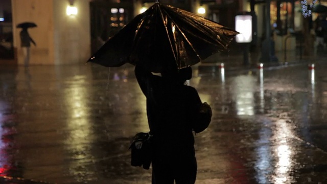 一位女士在雨中撑着伞等着过马路视频素材