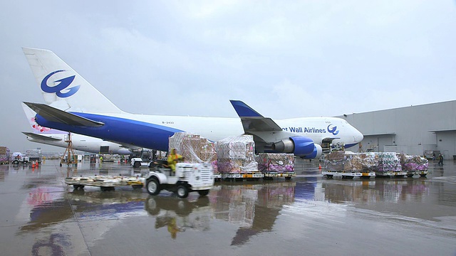 WS长城航空货运飞机(波音747-400F)在被雨打湿的停机坪上，卡车经过前景/美国德克萨斯州达拉斯沃斯堡DFW国际机场视频素材