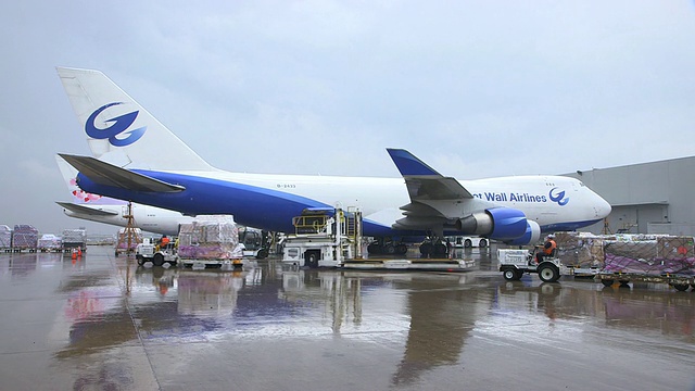 ZO长城航空货运飞机(波音747-400F)在被雨打湿的停机坪上，前方是正在运送货物的卡车/美国德克萨斯州达拉斯沃斯堡国际机场视频素材