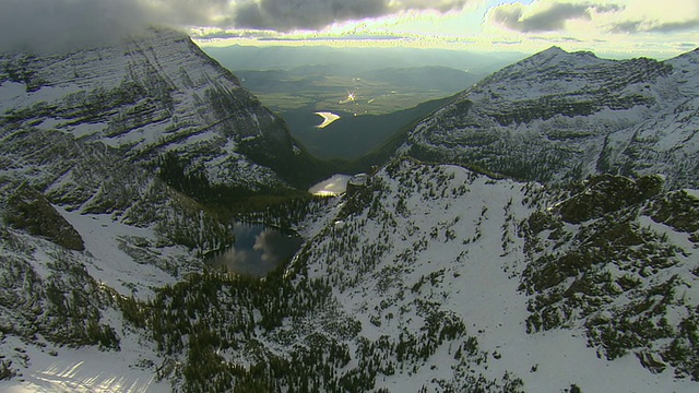 WS AERIAL Shot的云在被雪覆盖的山脊在Mission山揭示路西法湖下面/圣伊格内修斯，蒙大拿，美国视频素材