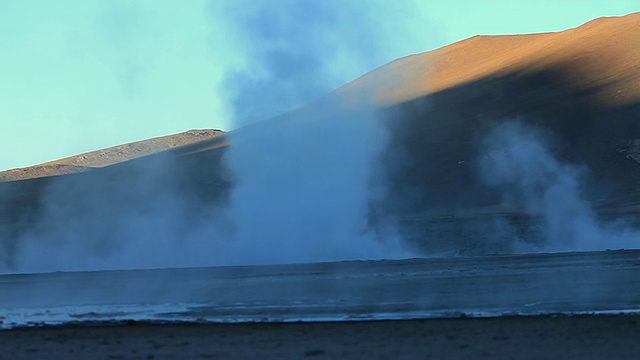 WS间歇泉蒸汽上升与低棕色山与阳光/ Geiser del Tatio，阿塔卡马沙漠，智利视频素材