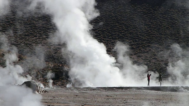 智利阿塔卡马沙漠，妇女们站在间歇泉中拍照，欣赏从地面/ Geiser del Tatio冒出的蒸汽视频素材