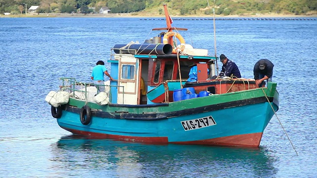 三名男子在渔船上拉绳/卡斯特罗，Isla Grande de ChiloÌ©，智利视频素材