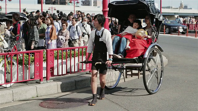 一名人力车车夫拉着一辆jinrikisha穿过东京街道/日本东京视频素材