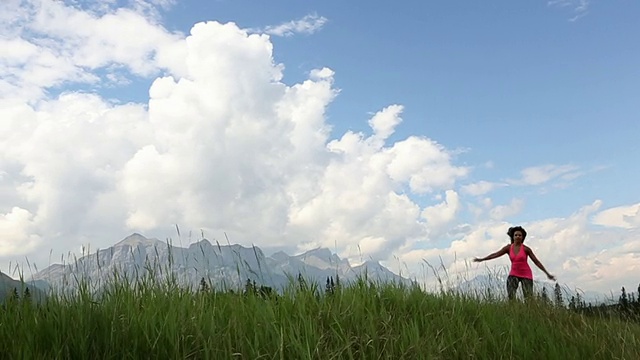 女子在高山草地上跳跃舞蹈的慢动作视频素材