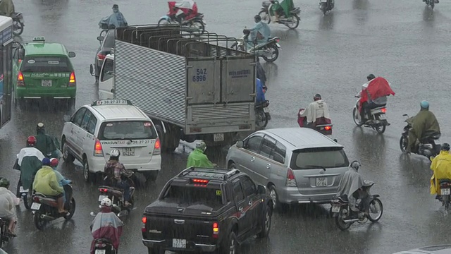 MS摄于越南西贡胡志明市大雨中的自行车、汽车和摩托车街道交通视频素材