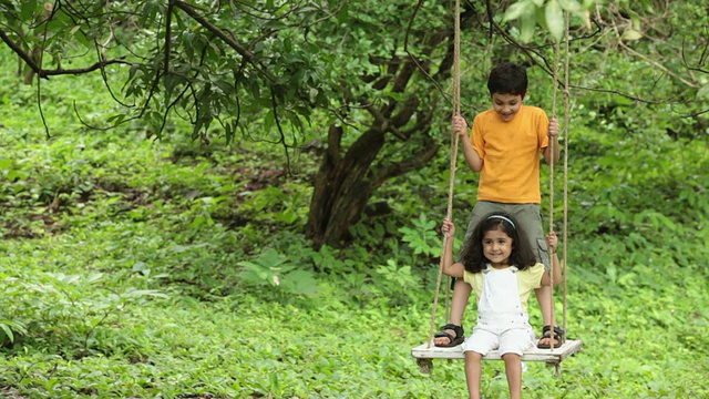 印度马哈拉施特拉邦，Malshej Ghat，两个孩子在公园里荡秋千视频素材