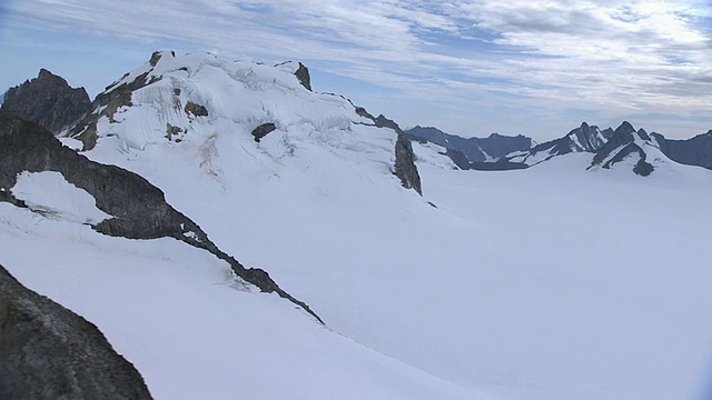 宽镜头空中跟踪(右)崎岖的山峰与积雪的山口接壤。/阿拉斯加,美国的视频素材