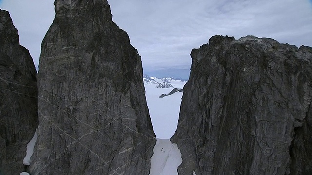 “广角空中推射”崎岖的山峰与雪山的山口接壤。/美国阿拉斯加”视频素材