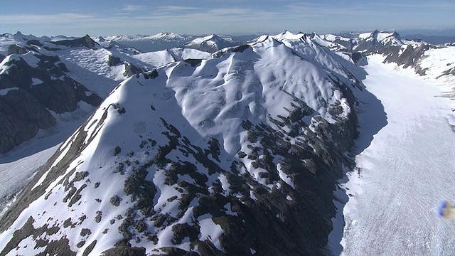 长镜头空中跟踪——雪覆盖了山坡和参差不齐的山峰。/阿拉斯加,美国的视频素材