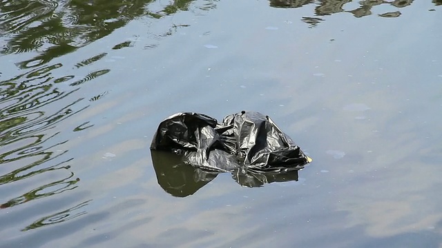 垃圾袋漂浮在水上。视频素材