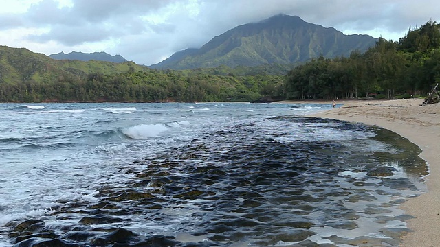 一名男子走在美国夏威夷考艾岛海滩的岩石海岸线上视频素材