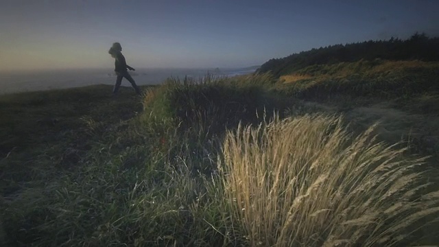 美国俄勒冈州，布兰科角，女士行走在俯瞰海洋的小径上视频素材