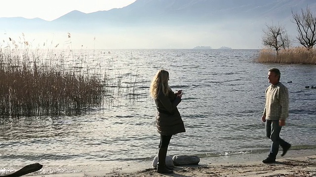 男人和女人在湖边，然后看照片视频素材