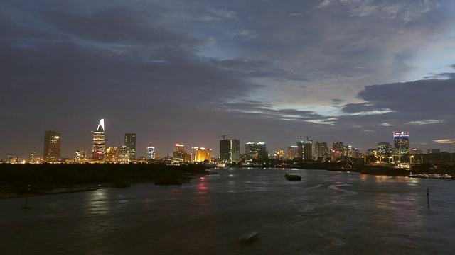 从白天到夜晚，西贡河上的船只和驳船与胡志明市的天际线连成一片视频素材