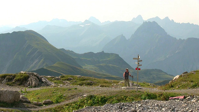 图为一名登山者在德国巴伐利亚的内伯霍恩山(Mount Nebelhorn)欣赏美景的照片视频素材