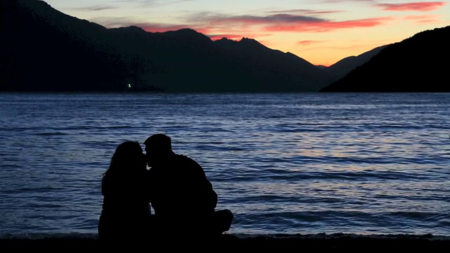 异性恋夫妇看日落和在海滩上接吻视频素材