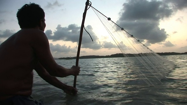 日落时分用网捕鱼的男子/ Ilha dos Lencois, Maranhao，巴西视频素材