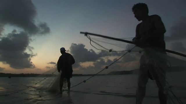 日落时分，两名男子在用网捕鱼/ Ilha dos Lencois, Maranhao，巴西视频素材