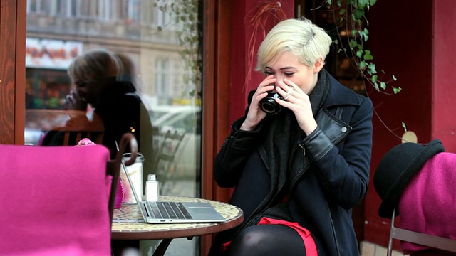 MS Shot of Woman drinking hot tea at cafe outside while talking and smiling on Skype /柏林，德国视频素材