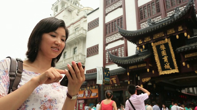 在豫园旅游市场使用智能手机的年轻女性视频素材