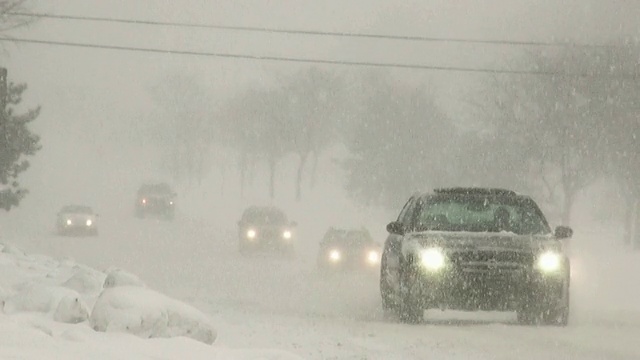 冬天的暴风雪。在湿滑的道路上车辆来往。视频下载