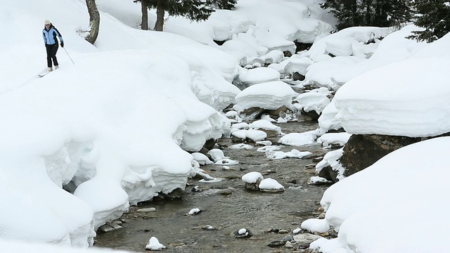 滑雪者从小溪上方的雪岸下，沿着滑雪道滑行视频素材