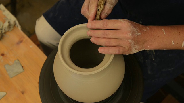 在德国巴伐利亚州的pottery / Landshut，女陶工在陶轮上完成陶罐成型视频素材