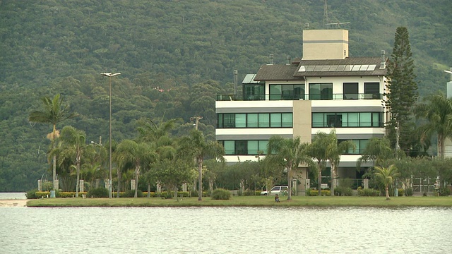 Florianopolis [FlorianÃ³polis]，巴西[Brasil]的水边住宅/公寓，有树木覆盖的山丘和坐在水边的人视频素材