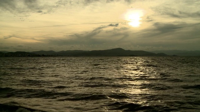 引人注目的太阳和多云的天空，俯瞰巴西Florianopolis海湾[FlorianÃ³polis]，朝向黑暗起伏的山丘。视频素材