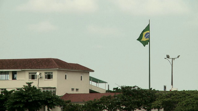 巴西国旗[Bandeira do Brasil]飘扬在红色瓦屋顶的旗杆上，巴西里约热内卢[巴西]视频素材