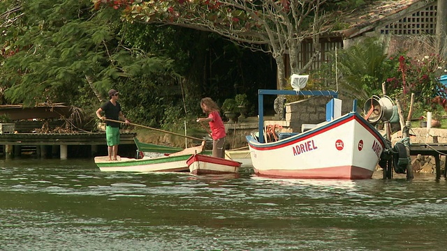 巴西弗洛里亚诺波利斯(Florianopolis) [FlorianÃ³polis]郊区[巴西]，年轻人在非常小的船上，用大木棍推进。视频素材