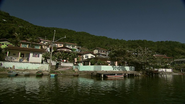 沿着非常静止的水道行驶，经过在巴西Florianopolis (FlorianÃ³polis)郊区山上建造的河边住宅[巴西]视频素材