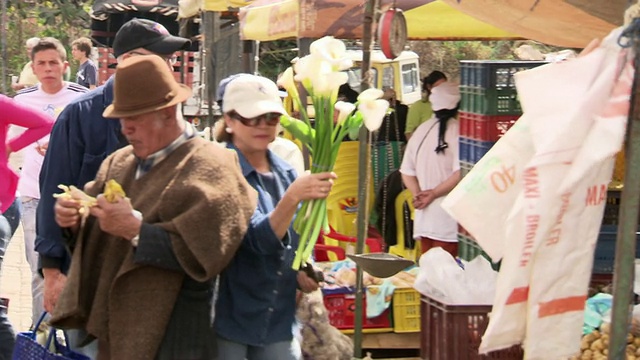 Tourists carrying recently bought lillies on busy thoroughfare, Villa De Leyva market, Villa De Leyva, BoyacÃ¡ department, Colombia视频素材