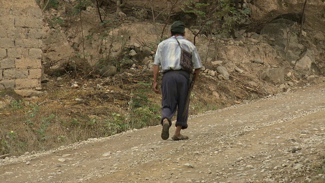 秘鲁亚马孙地区一男子手持大砍刀走在砾石路上[PerÃº]视频素材