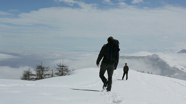 徒步旅行者穿过积雪进入多雾的草地，为了队友视频素材