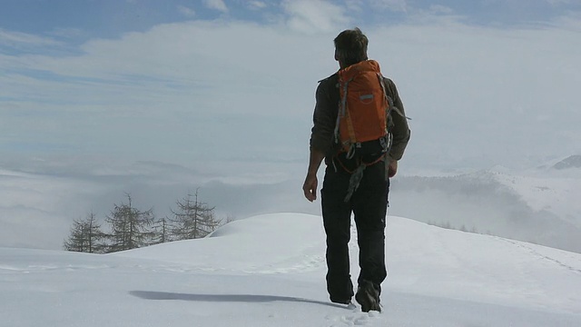 一名徒步旅行者穿过积雪，进入多雾的山地草地视频素材