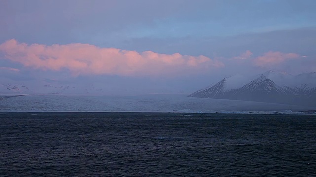 在冰岛的Jokulsarlon湖，日出的辉光照亮了Breidamerkurjokull冰川和雪山上的云视频素材