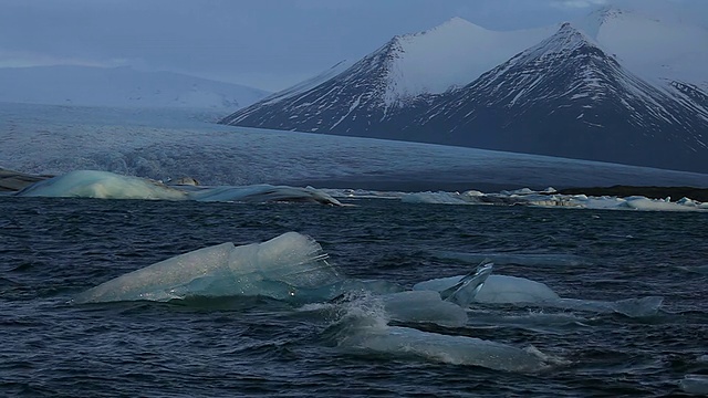 阵风女士和波粉碎冰川漂浮在Jokulsarlon泻湖Breidamerkurjokull冰川和冰雪覆盖山/冰岛视频素材