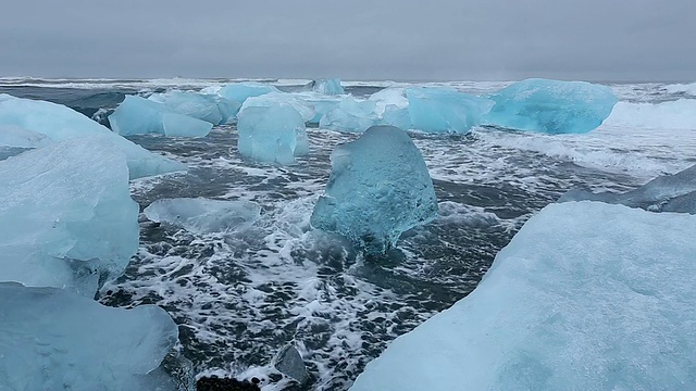 在冰岛Jokulsarlon河口的Jokulsa冰山海滩上，海浪翻滚着冲刷冰川视频素材