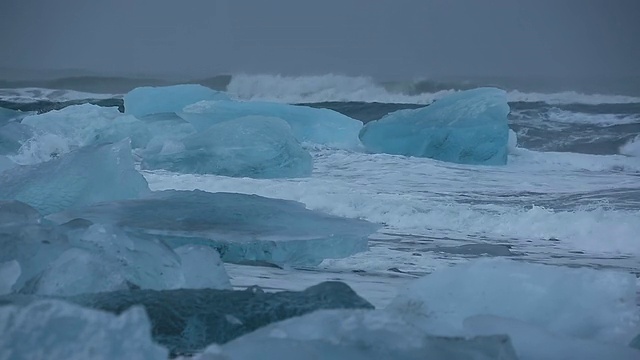 在冰岛Jokulsarlon河口的Jokulsa冰山海滩上，海浪翻滚着冲刷冰川视频素材