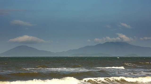 海浪翻滚到阳光沙滩和云移动山/会安，广南，越南视频素材