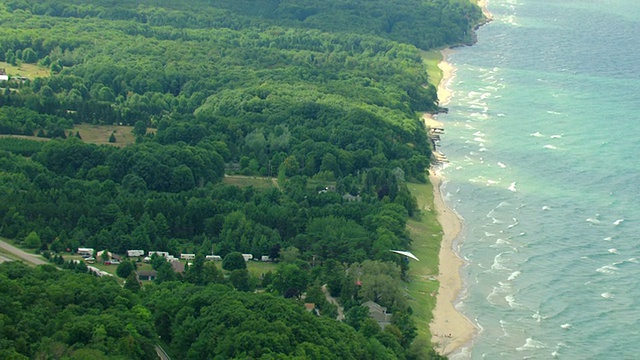 WS AERIAL ZO视图跟踪拍摄悬挂滑翔机在空中飞过密歇根湖和海岸线/阿卡迪亚，密歇根州，美国视频素材