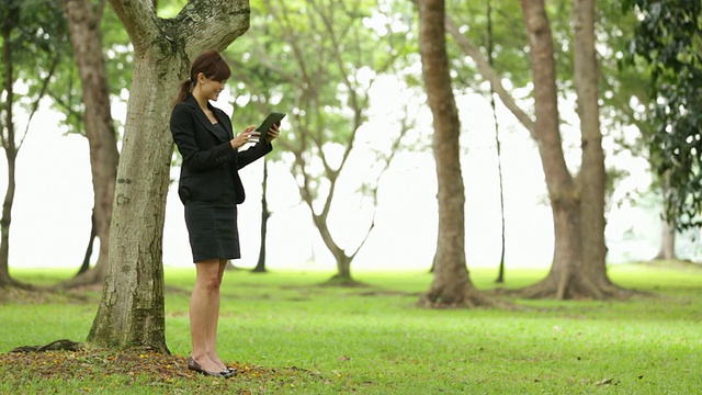 亚洲女商人在公园户外使用平板电脑视频素材