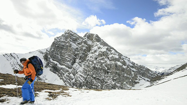 一个登山家穿过山下白雪覆盖的草地视频素材