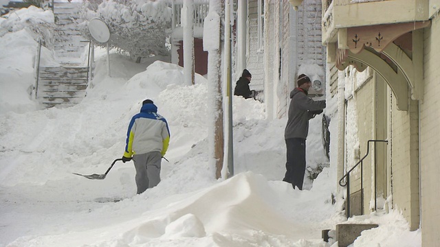 三个男人铲雪，大雪堆和风吹视频素材