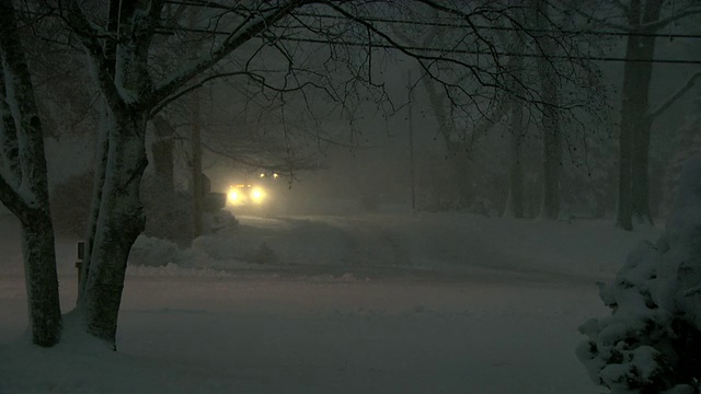 在暴风雪期间，扫雪机夜间在居民区的街道上视频素材