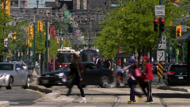 在加拿大多伦多市中心的Spadina大街上，一群人穿过一个繁忙的十字路口。视频素材