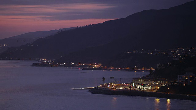 马里布海岸线和太平洋海岸高速公路在黄昏时分，车灯沿着弯弯曲曲的海岸线飞驰视频素材